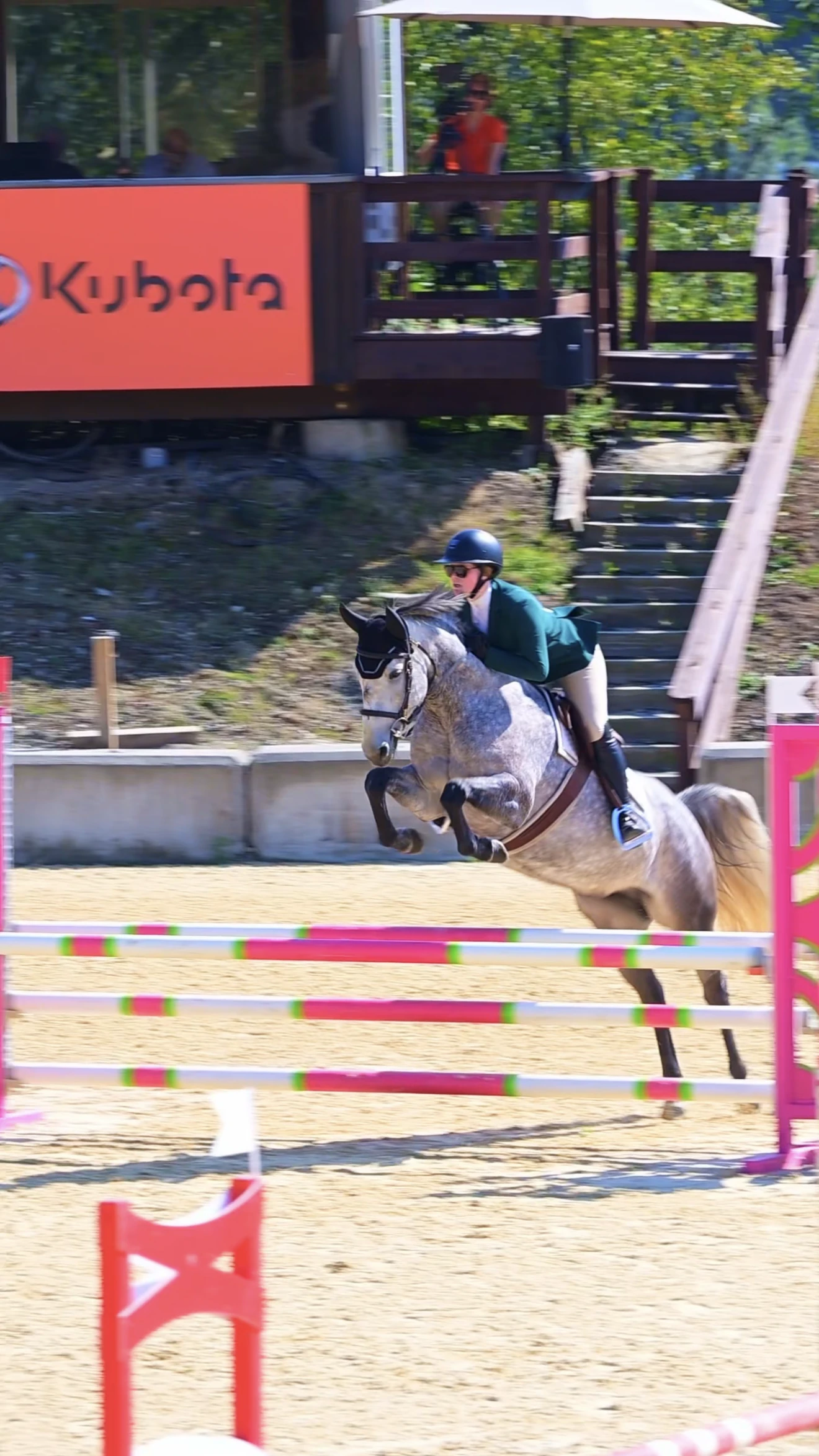 Quintessence LLA and rider jumping a bright pink-and-green rail